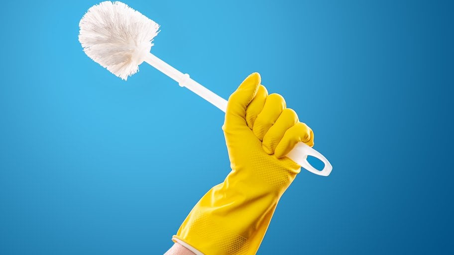 a hand wearing a rubber glove holding a toilet brush